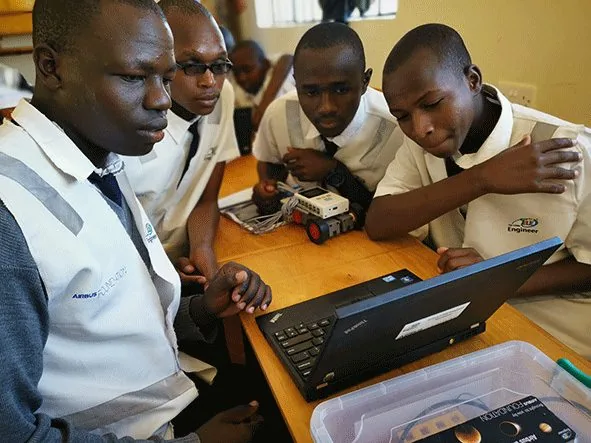 Students working with an instructor at computers during an outreach programme
