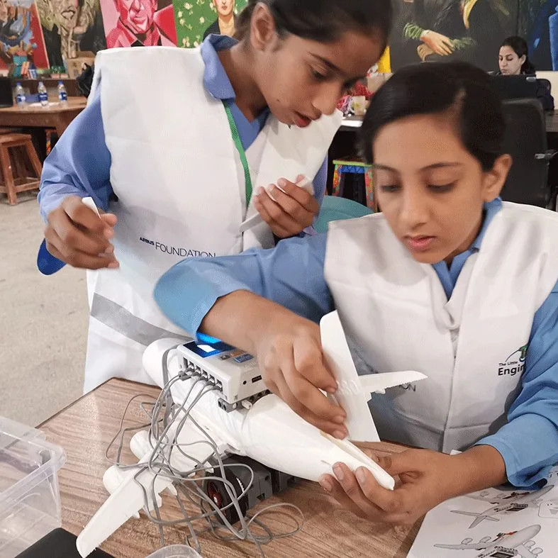 Students in lab coats assembling an aircraft model during an aviation workshop