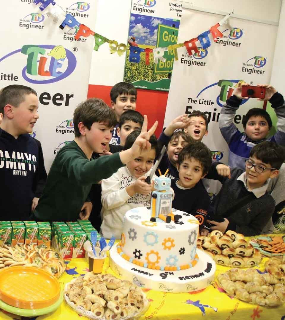 Children celebrating a Little Engineer themed birthday party with a robot cake
