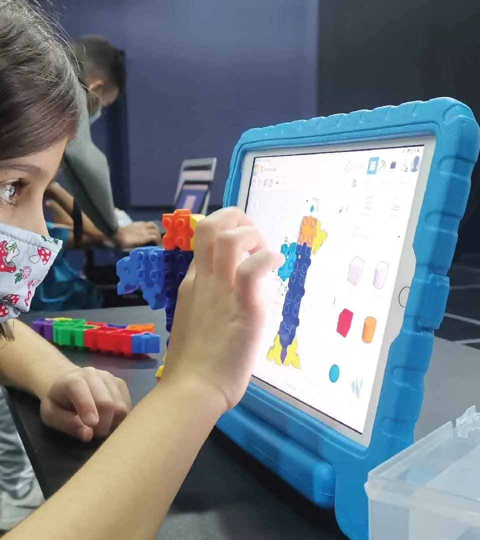 A child assembling a coded model while following a build on a tablet